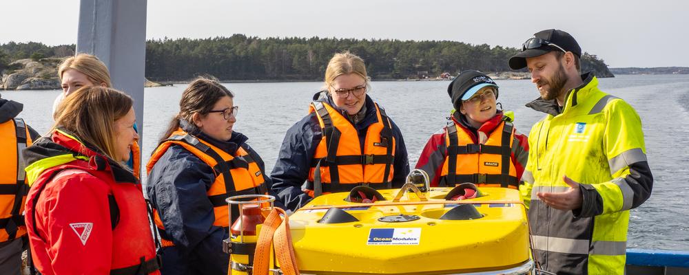 Students on aft deck watching a yellow remotely operated vehicle