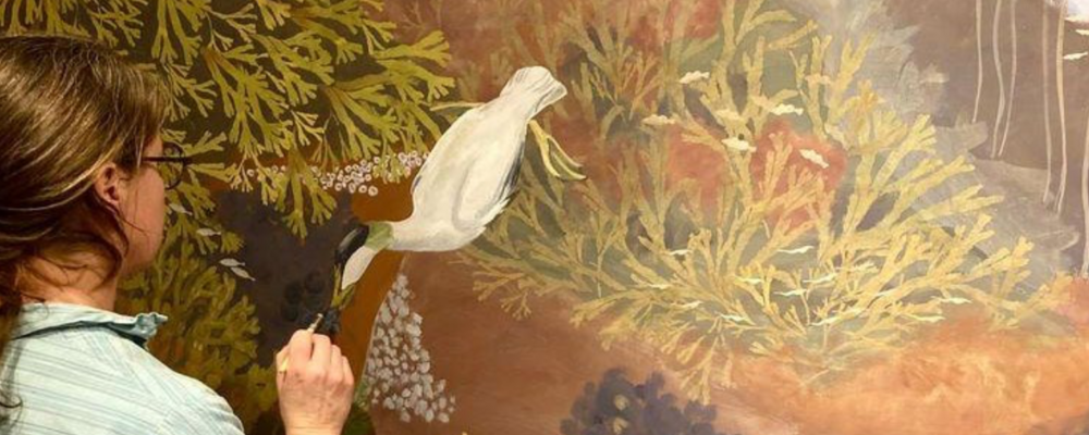 Bild på målare som målar på vägg