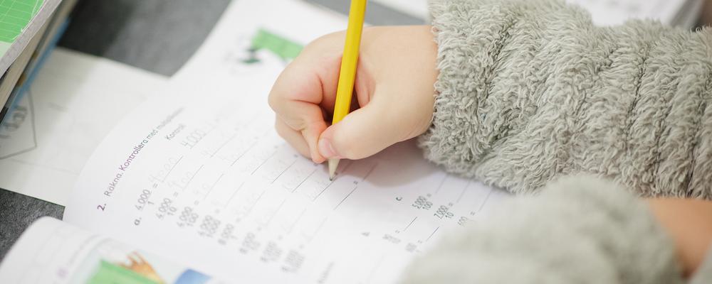 Mattebok och hand på elev som räknar matematik