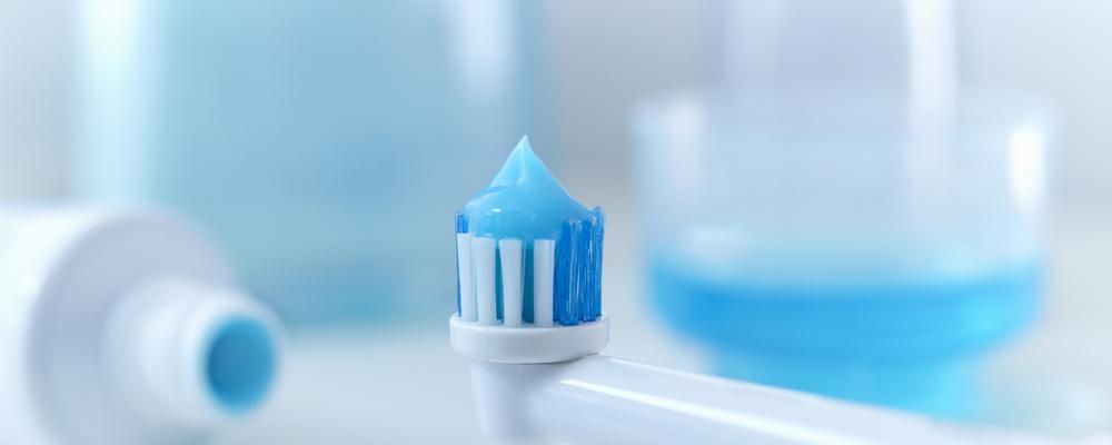 Tandborste, tandkräm, mellanrumstandpetare mot ljus bakgrund.