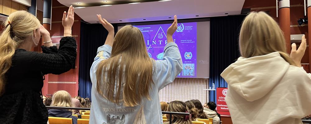 glada studenter i rockar hoppar och applåderar under intåg in i sal