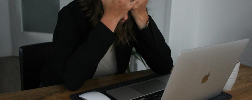 Person vid dator med ansiktet i händerna.