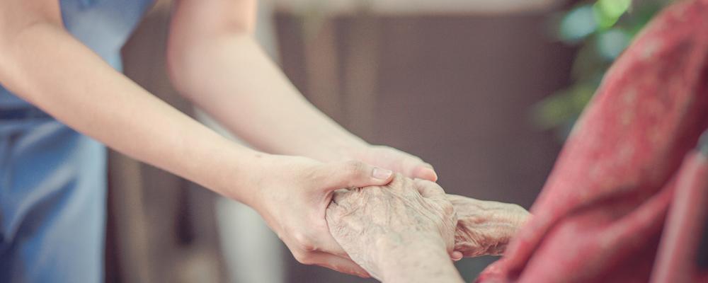 Sjuksköterska håller äldre persons händer
