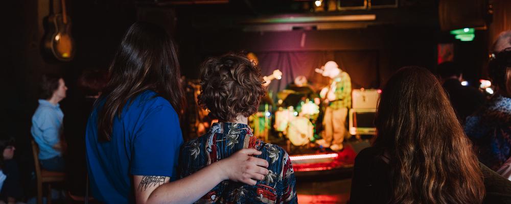 En grupp personer tittar i riktning mot en scen där några musiker framträder