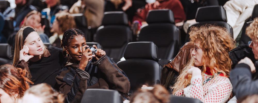 Kvinnliga filmstudenter tar foton på varann i en biosalong