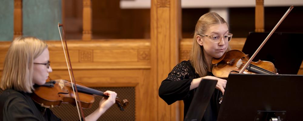 Two persons playing violins
