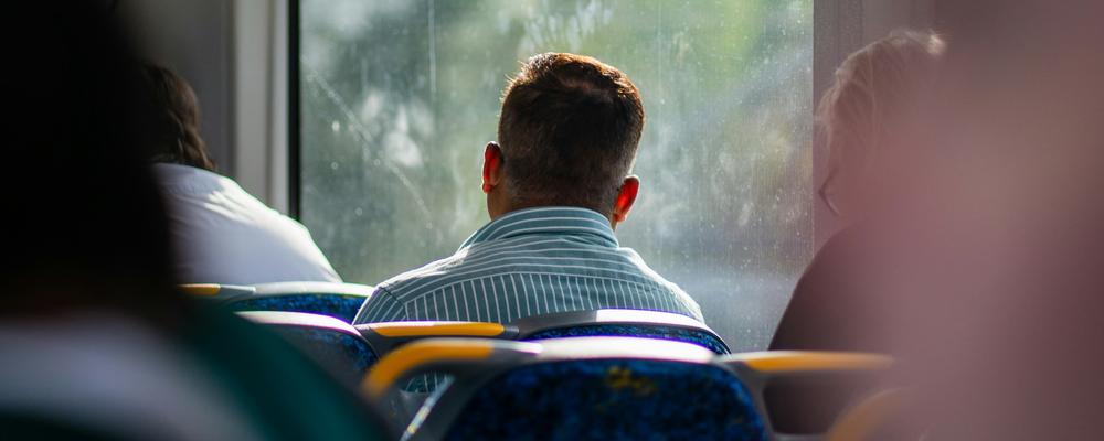 En person, sedd bakifrån, sitter på en buss
