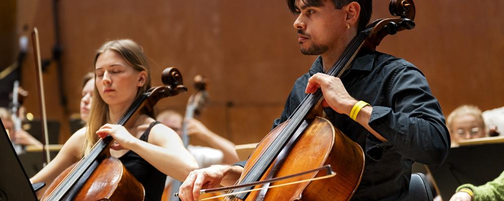 Two persons playing celli