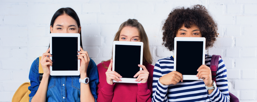 Tre barn som håller upp varsin surfplatta framför sig