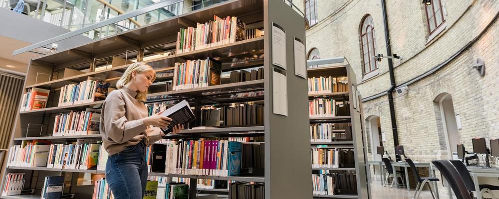 Student väljer bland böcker i biblioteket