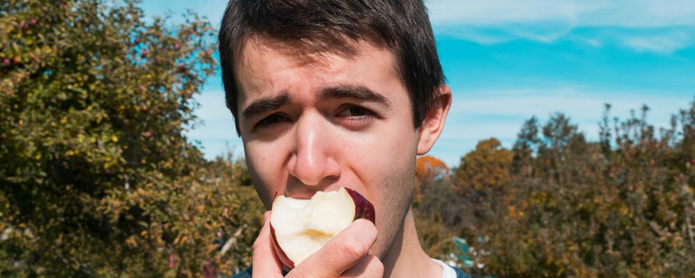 En man äter ett äpple.