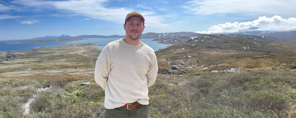 ung man står i ett fjällandskap och tittar in i kameran 