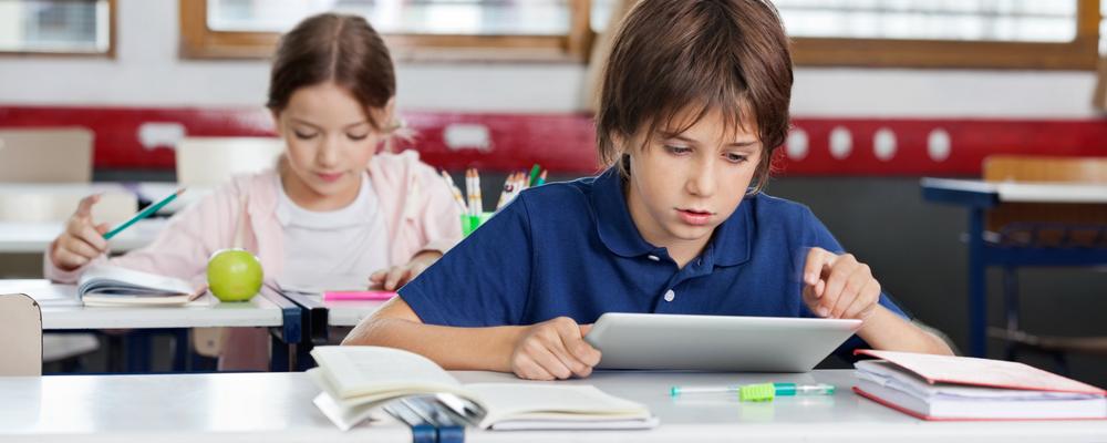 Pojke i klassrum läser på en surfplatta