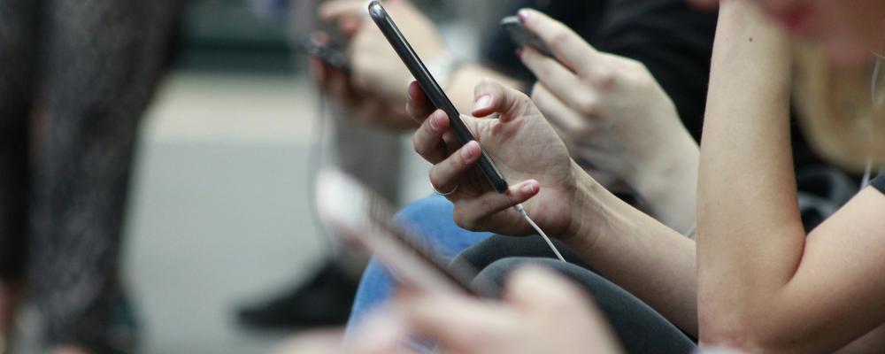 Människor som tittar på sina mobiler.