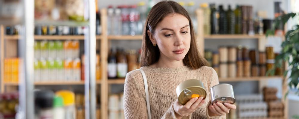 Kvinna som jämför två konservburkar