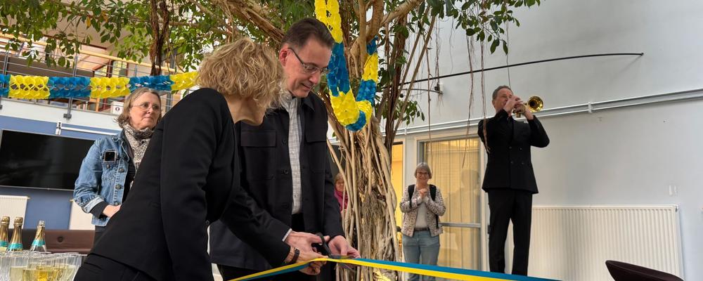 Prefekt Jan Borén står i mitten och klipper ett blågult band vid invigningen av UGot ReWork i Hälsovetenskapligt centrum. Runt omkring finns flera deltagare, och i bakgrunden spelar en trumpetare under ceremonin.