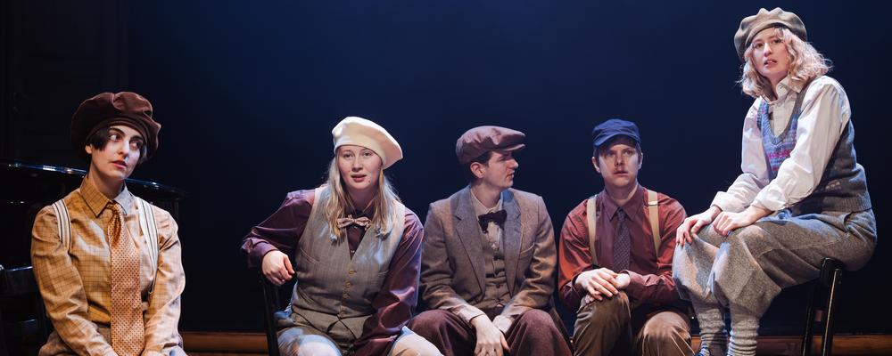 Flera operasångare sitter på rad på scen