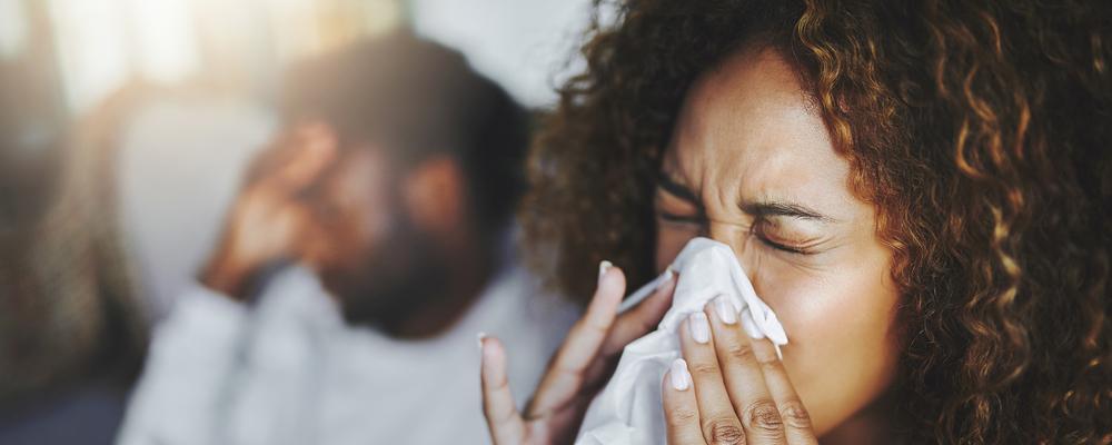 sjuk man och kvinna i soffa snyter sig