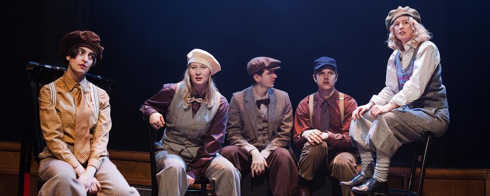 Fem personer sitter på scen i en operaföreställning