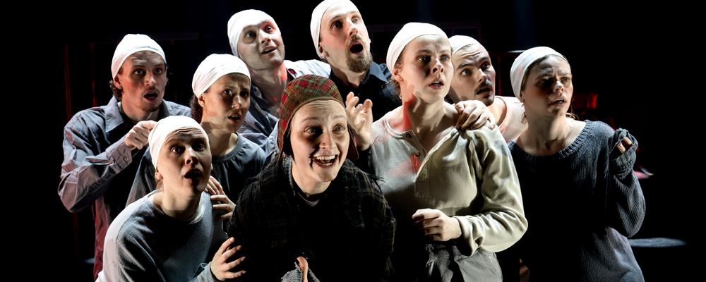 En grupp personer trängs i en klunga på scen