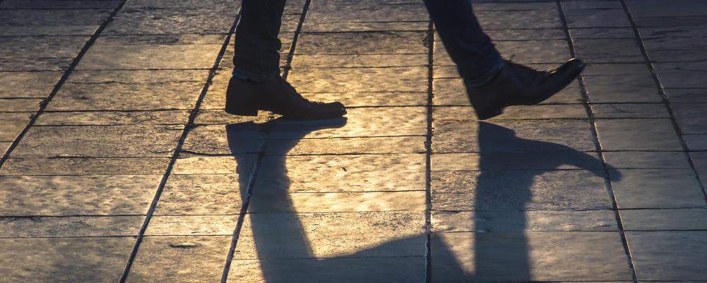 En man går på gata i motljus