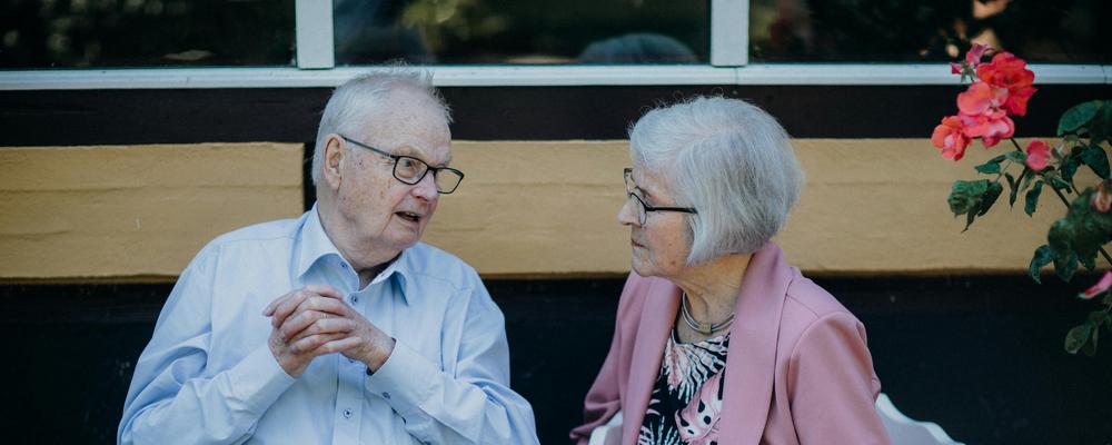 En man och en kvinna sitter utomhus på varsin stol och pratar