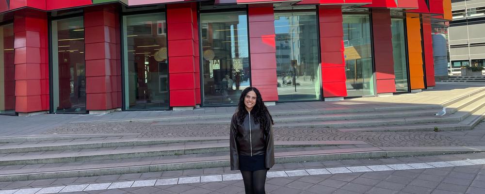 Bild på en tjej framför en röd byggnad