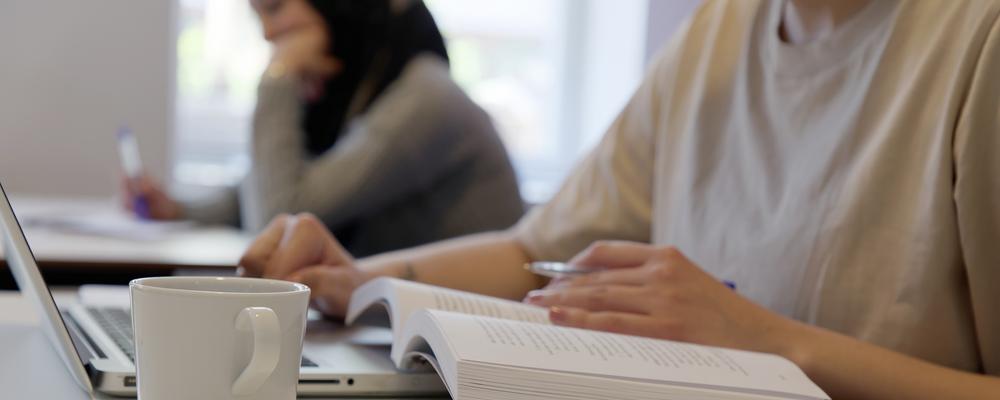 Närbild på student som läser kurslitteratur