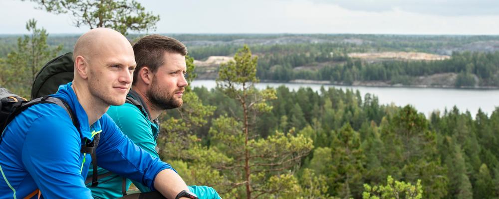Två män sitter på ett berg och blickar ut över landskapet