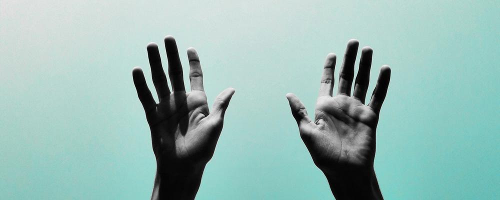 Image of two hands raised with a blue background