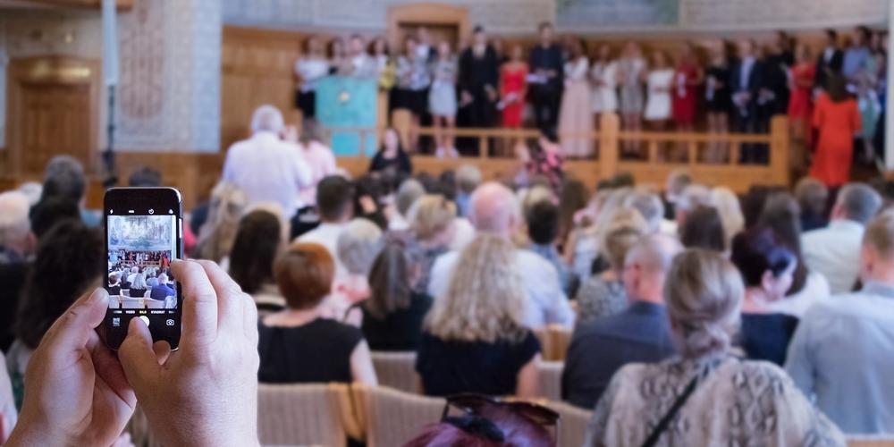 Någon fotograferar med sin mobil under en terminsavslutning