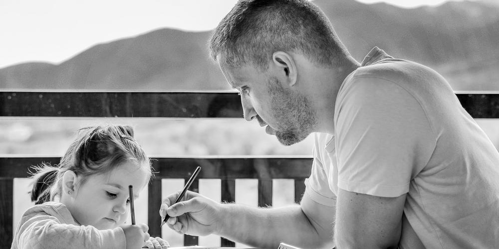 Little girl drawing with her father outside
