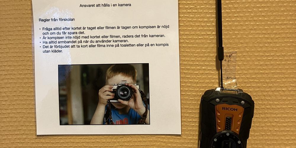 En vägg med en lapp med instruktioner och en kamera hängandes