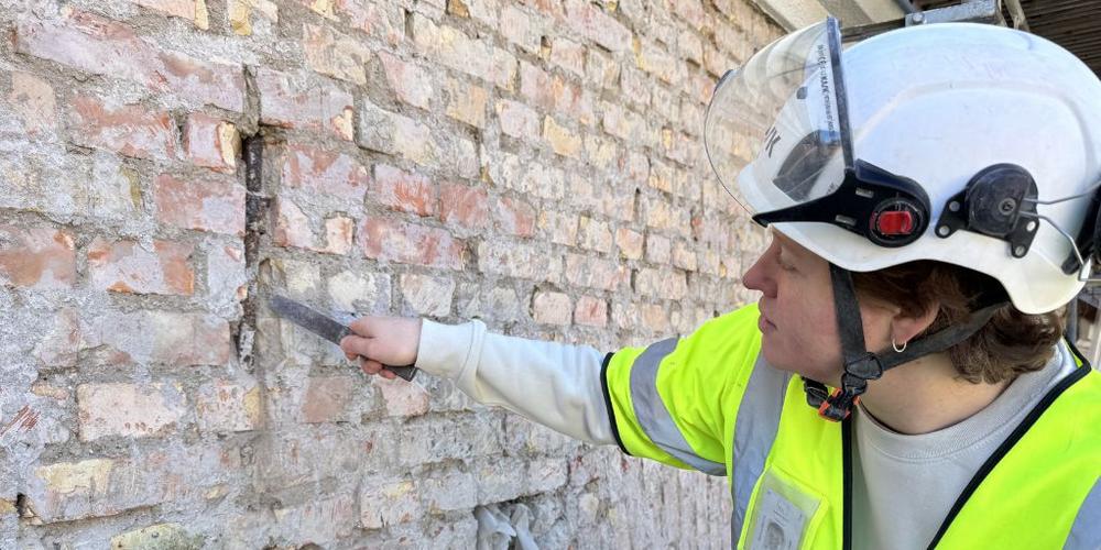 Alumn undersöker husfasad, foto.