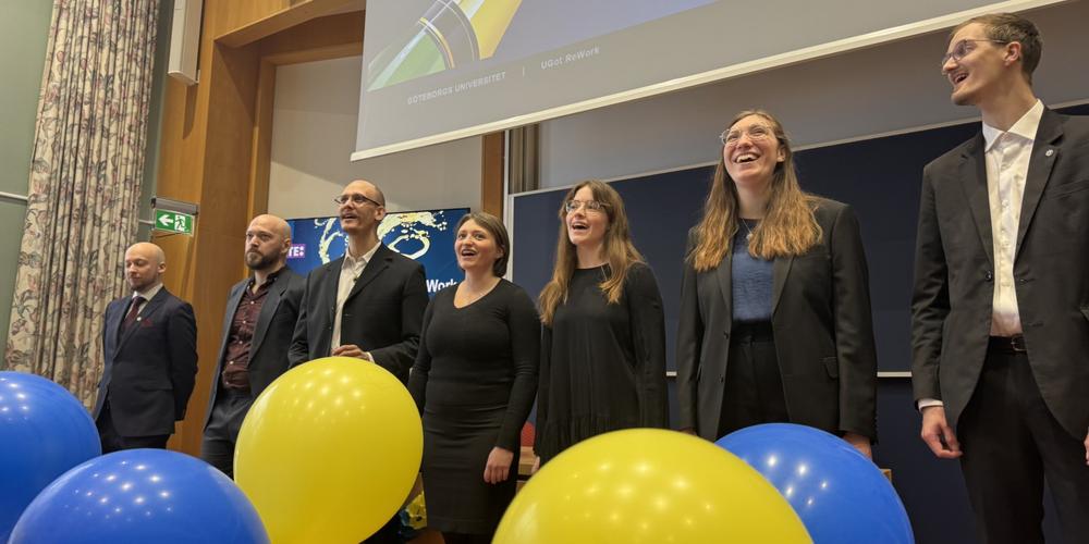 Chorus Acusticus sjunger under invigningen av UGot ReWork i en hörsal, med blå och gula ballonger i förgrunden.