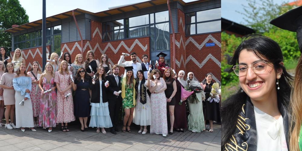 Examensstudenter poserar utanför campusbyggnad, två studenter i förgrunden.