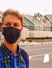 Björn Fondén with a face mask in front of a building with many flags outside
