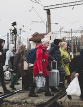Människor som just klivit av tåget i staden Lviv i västra Ukriana bär sitt bagage över spåren. Bilden tog den 3 mars, 2022.