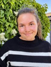 glad tjej i 20-årsåldern fotograferad vid en blommande syrénbuske