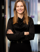 Leende kvinna i svart klädsel och med armarna i kors.