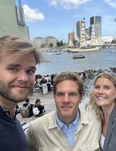 tre personer poserar för kameran, i bakgrunden syns en båt