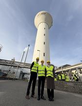 tre personer i gula västar står framför ett torn