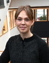 Frida som studerar på HCAI står i institutionens trappa.