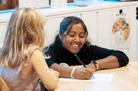 Lärare och elev samarbetar vid skolbänken.