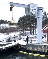 Crane lifting boat wit outboard engine from the water