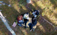 Image from drone over students relaxing in the woods.