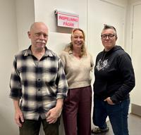 Tre personer framför en inspleningsskylt