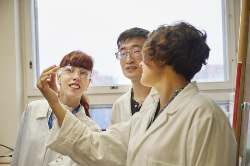 Doctoral students in gathered around a testing tube.