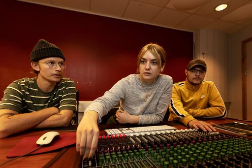 Tre Musik- och ljudproduktionsstudenter vid ett mixerbord