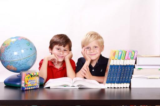 Two young boys sitting with a globe and their books